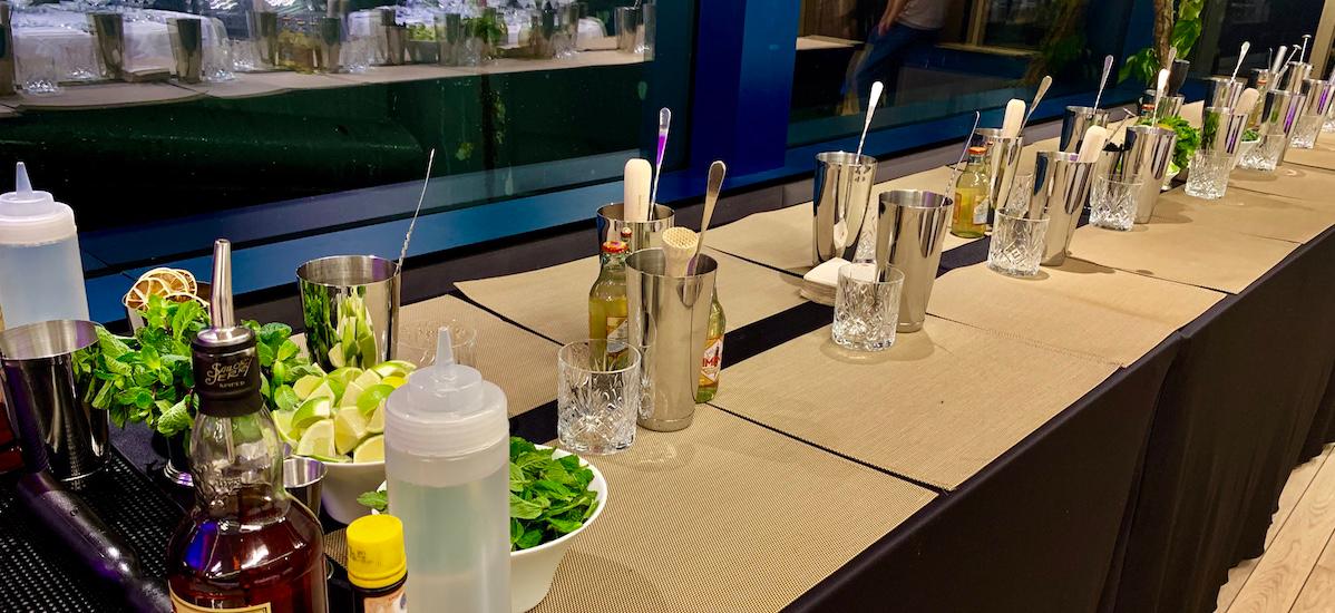 atelier coktail avec des participant souriant, mélangeant des ingrédients et suivant les instructions du barman.